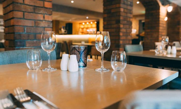 Restaurant table at Wild Pheasant Hotel & Spa set with glasses and cutlery, ready for guests, highlighting the elegant dining setup.